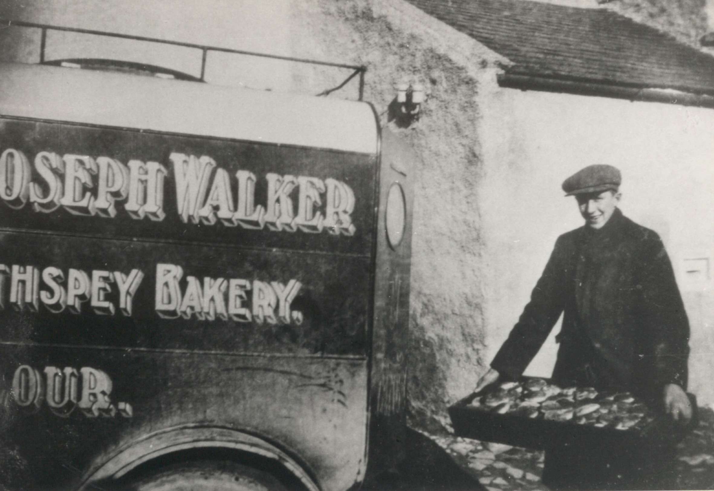 a vintage photo of Walkers shortbread van in black and white with man carrying a tray of goods